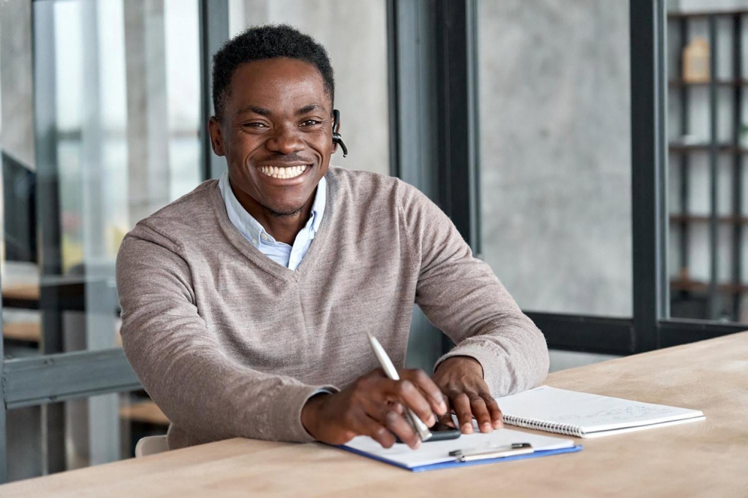 Smiling adult tutor at a training center desk in the UAE taking notes