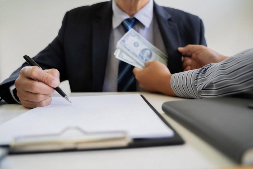 Businessman signing a contract while accepting cash, illustrating fraud risk in Dubai deals