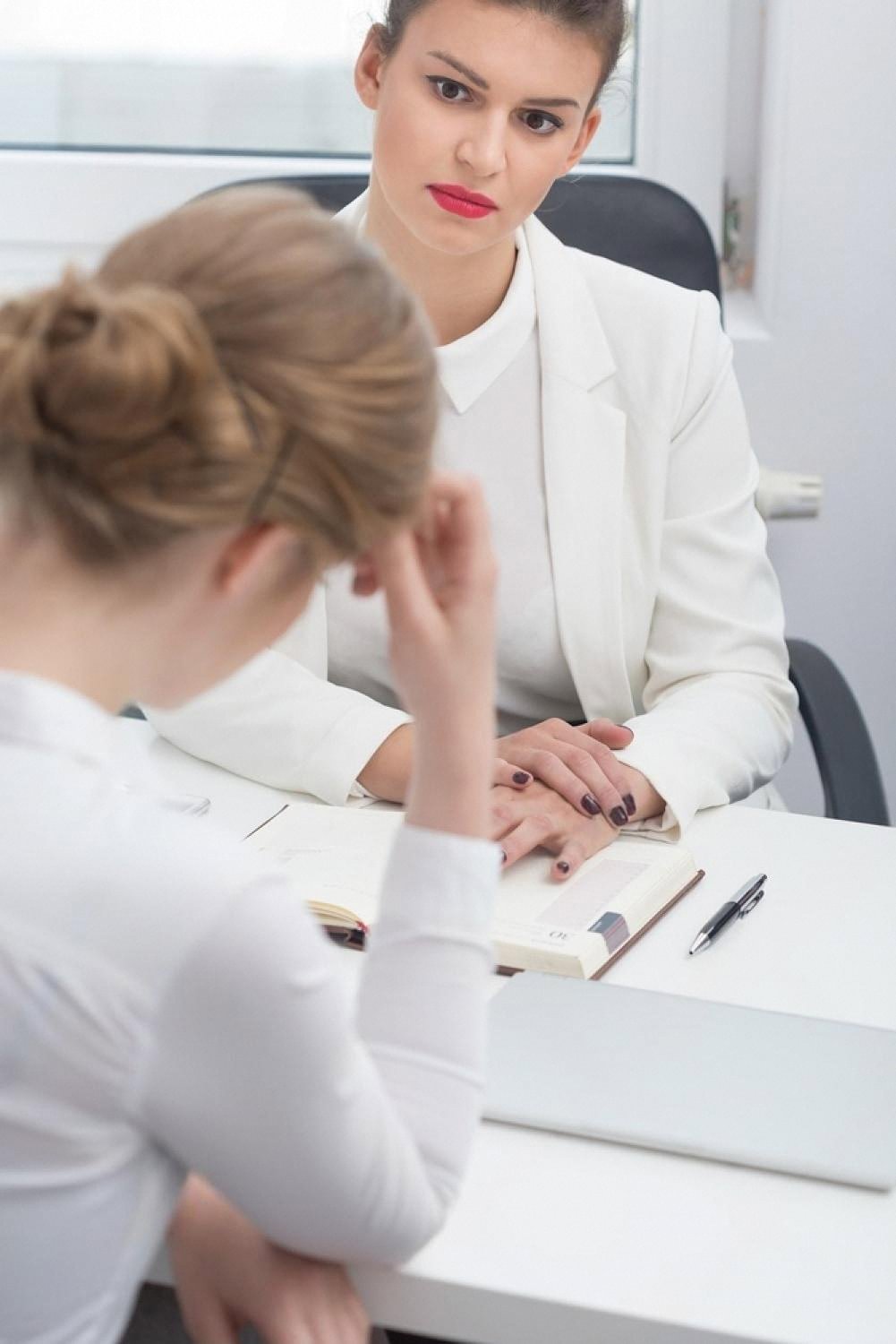 Tense business meeting between two women reviewing documents in a UAE office